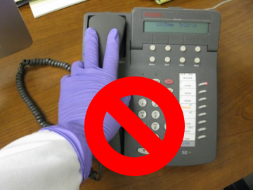 Gloved hand touching a desk telephone with a red X
